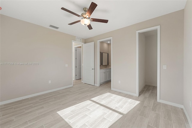 unfurnished bedroom with connected bathroom, a walk in closet, light hardwood / wood-style floors, and ceiling fan