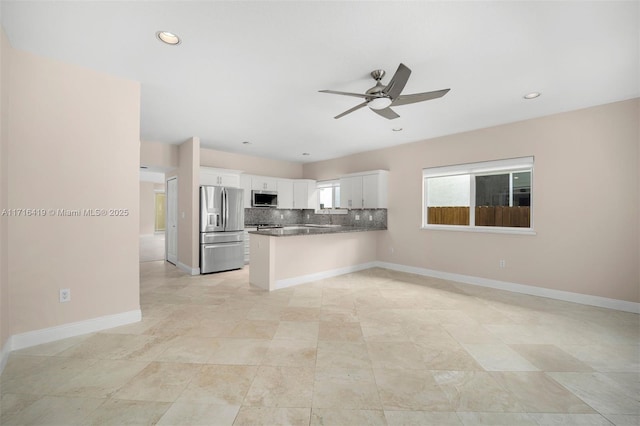 kitchen with kitchen peninsula, ceiling fan, decorative backsplash, appliances with stainless steel finishes, and white cabinetry