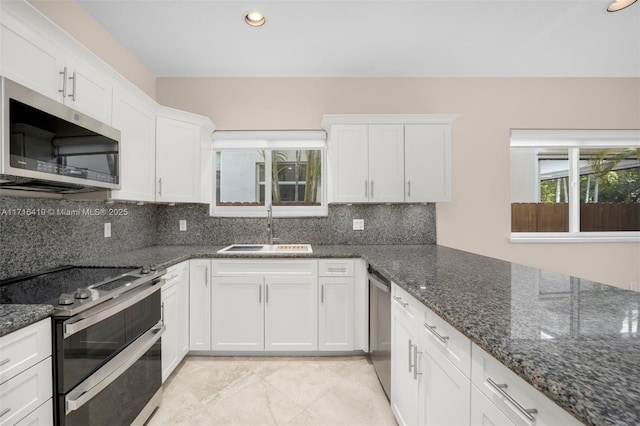 kitchen featuring dark stone countertops, white cabinetry, sink, and appliances with stainless steel finishes