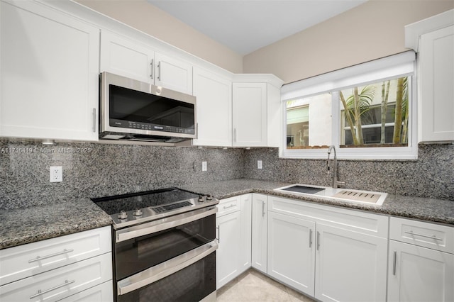 kitchen featuring backsplash, white cabinets, sink, dark stone countertops, and appliances with stainless steel finishes