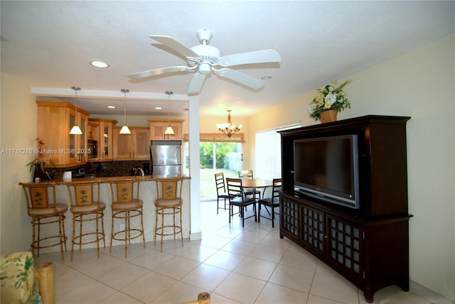 kitchen featuring kitchen peninsula, stainless steel refrigerator, hanging light fixtures, and dark stone countertops