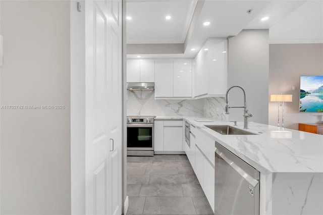 kitchen with sink, stainless steel appliances, light stone countertops, decorative backsplash, and white cabinets