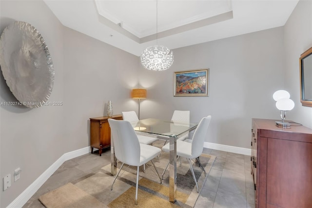 dining area with a chandelier, a tray ceiling, and ornamental molding