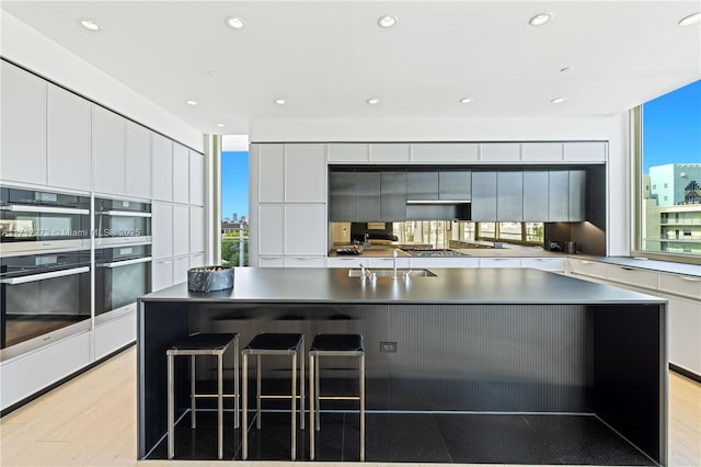 kitchen with white cabinetry, sink, an island with sink, and stainless steel appliances