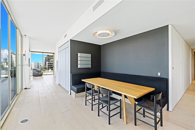 dining area with expansive windows and light hardwood / wood-style floors