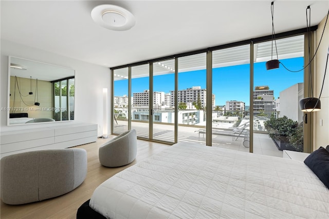 bedroom featuring access to exterior, light hardwood / wood-style flooring, and a wall of windows