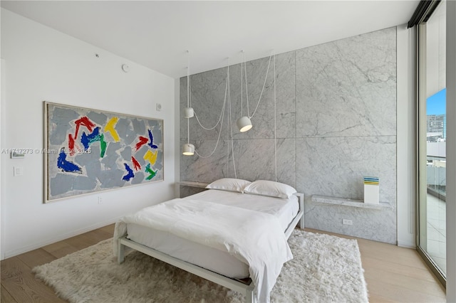 bedroom featuring a wall of windows, tile walls, and light hardwood / wood-style flooring