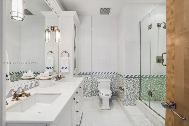 bathroom featuring vanity, tile patterned floors, toilet, tile walls, and a shower with shower door