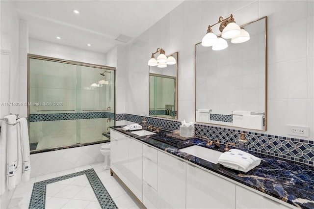 full bathroom with decorative backsplash, vanity, shower / bath combination with glass door, tile walls, and toilet