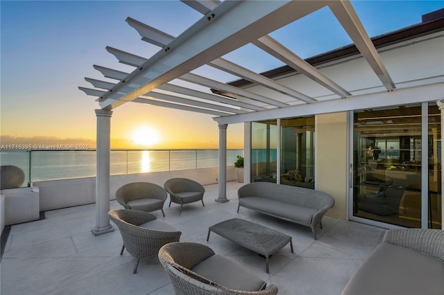 patio terrace at dusk featuring a pergola and a water view