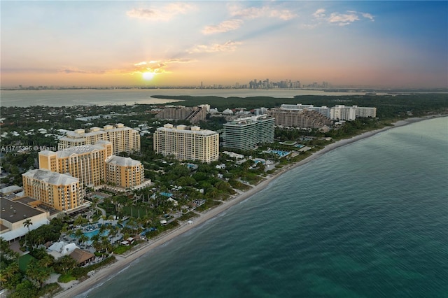 aerial view at dusk with a view of the beach and a water view