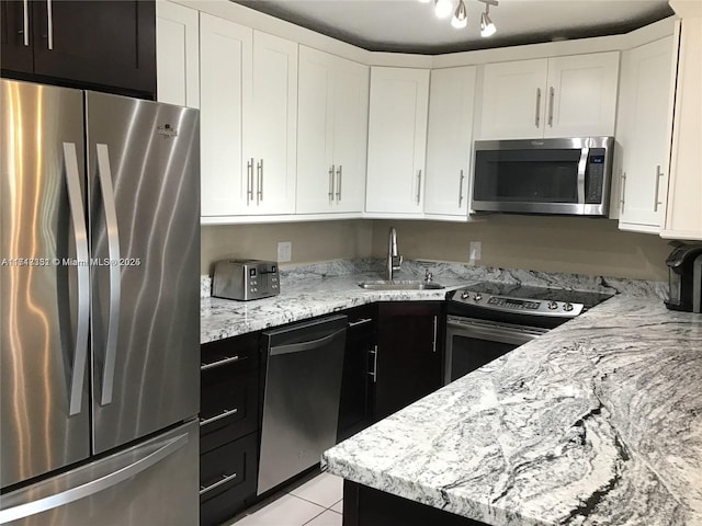 kitchen with white cabinetry, sink, stainless steel appliances, light stone counters, and light tile patterned floors