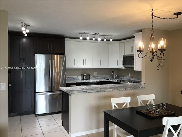 kitchen featuring pendant lighting, sink, light stone countertops, appliances with stainless steel finishes, and kitchen peninsula