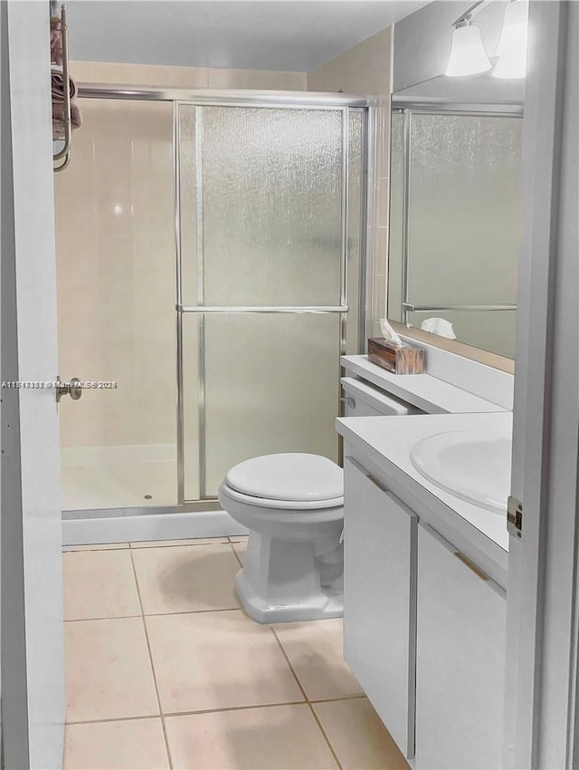 bathroom featuring tile patterned flooring, vanity, toilet, and a shower with door