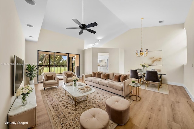 living room with high vaulted ceiling, light hardwood / wood-style floors, and ceiling fan with notable chandelier