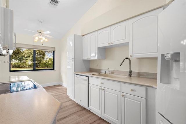 kitchen with dishwasher, white cabinets, vaulted ceiling, and sink