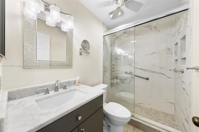 bathroom featuring vanity, toilet, an enclosed shower, and ceiling fan