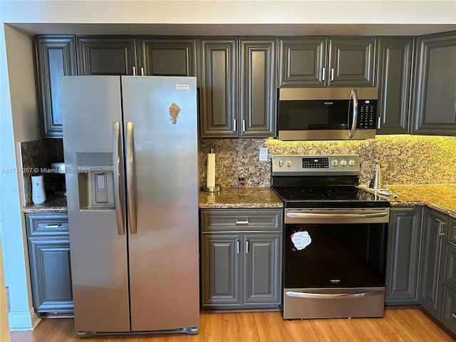 kitchen featuring light wood-type flooring, stone counters, and appliances with stainless steel finishes