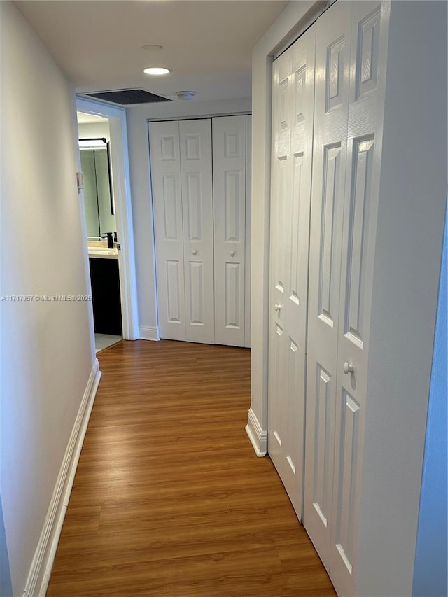 corridor with baseboards and wood finished floors