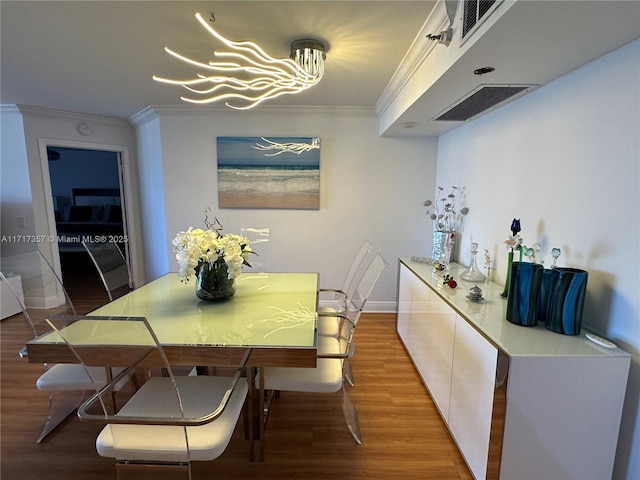 dining area featuring light wood-style floors, visible vents, crown molding, and an inviting chandelier