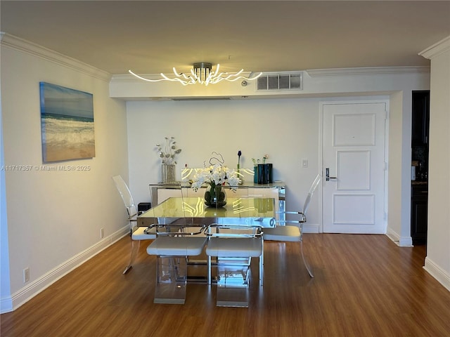 dining room with crown molding, wood finished floors, visible vents, baseboards, and an inviting chandelier