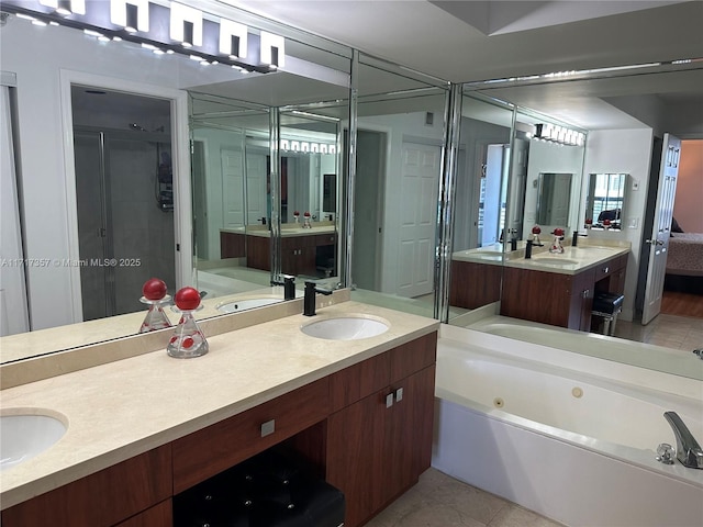 bathroom with double vanity, tile patterned flooring, a tub with jets, and a sink