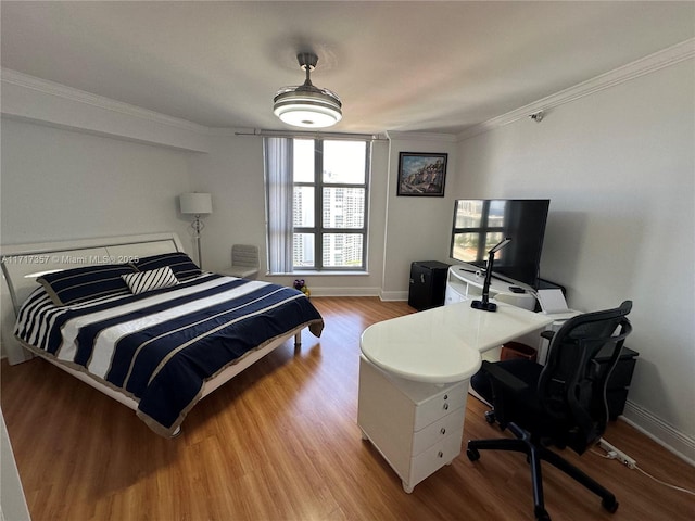 bedroom with ornamental molding, wood finished floors, and baseboards