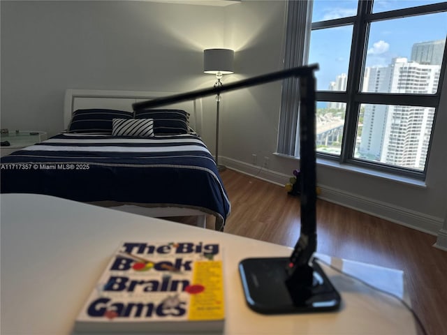 bedroom featuring a view of city, baseboards, and wood finished floors