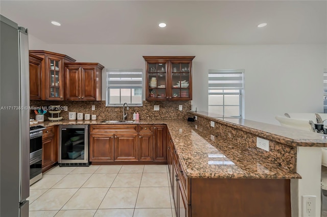 kitchen with beverage cooler, kitchen peninsula, sink, and decorative backsplash