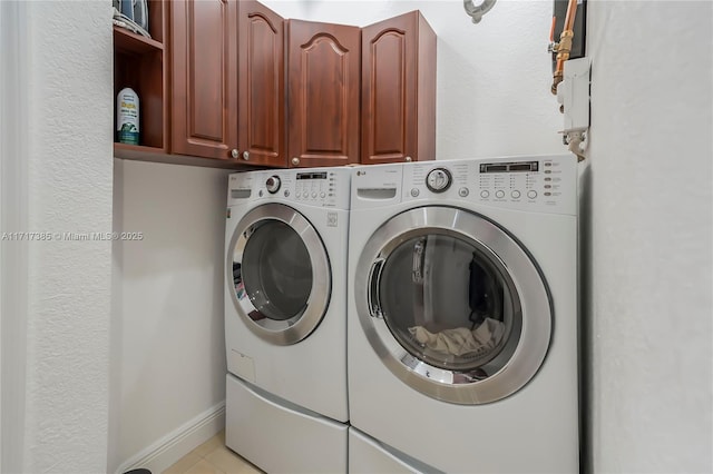 clothes washing area featuring cabinets and washer and clothes dryer