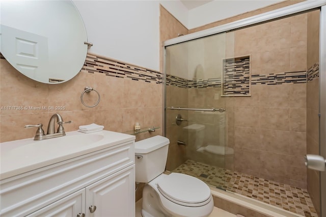 bathroom featuring vanity, tile walls, toilet, and walk in shower