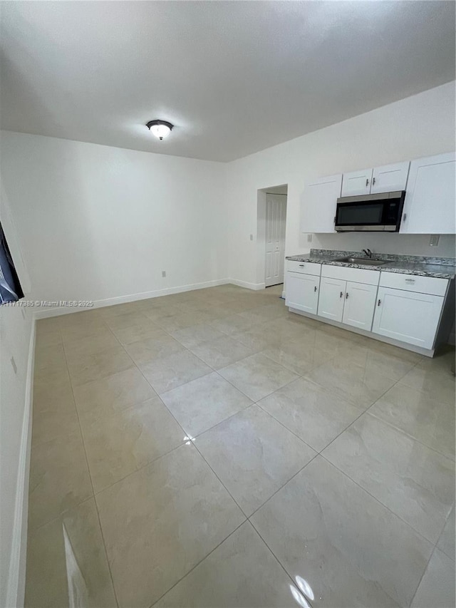 kitchen with white cabinetry, light stone countertops, sink, and light tile patterned floors