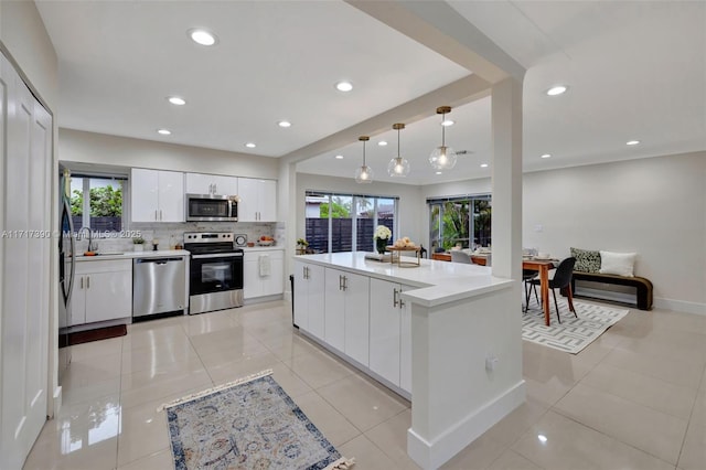 kitchen with white cabinets, decorative light fixtures, stainless steel appliances, and light tile patterned floors