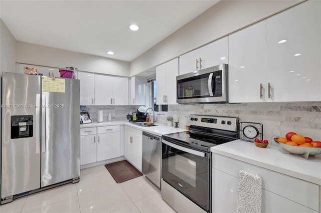 kitchen with sink, light tile patterned floors, appliances with stainless steel finishes, tasteful backsplash, and white cabinetry