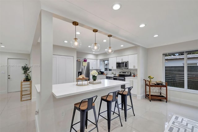 kitchen with white cabinets, a kitchen breakfast bar, stainless steel appliances, and hanging light fixtures