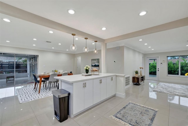 kitchen featuring pendant lighting, a center island, light tile patterned flooring, and white cabinetry