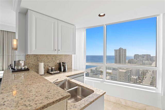 kitchen with white cabinets, a wealth of natural light, sink, and a water view