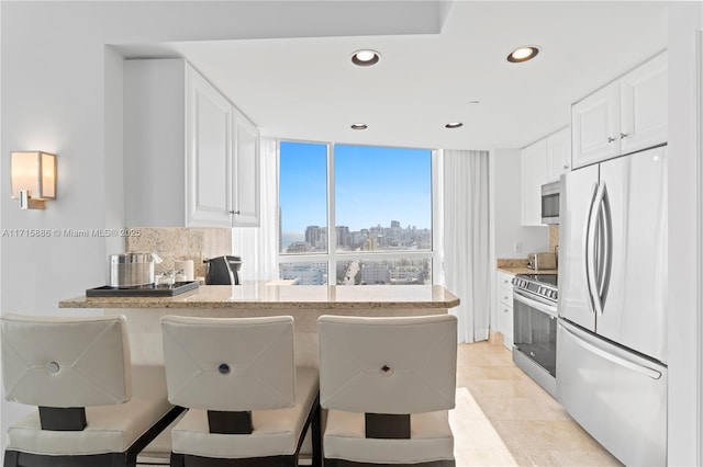 kitchen featuring kitchen peninsula, decorative backsplash, white cabinetry, and stainless steel appliances