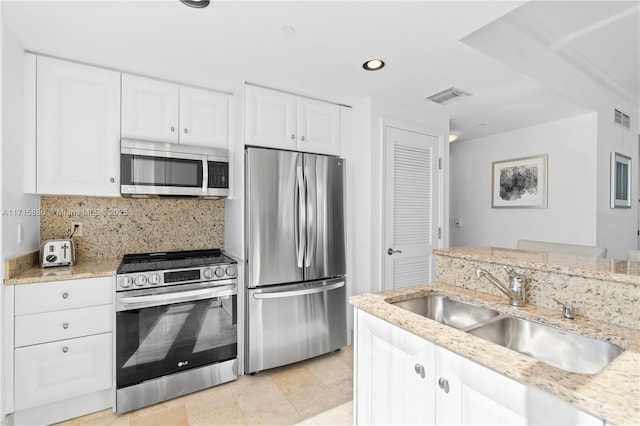 kitchen with decorative backsplash, light stone countertops, stainless steel appliances, sink, and white cabinetry