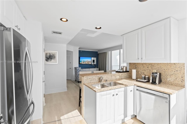 kitchen featuring white cabinets, sink, decorative backsplash, appliances with stainless steel finishes, and kitchen peninsula