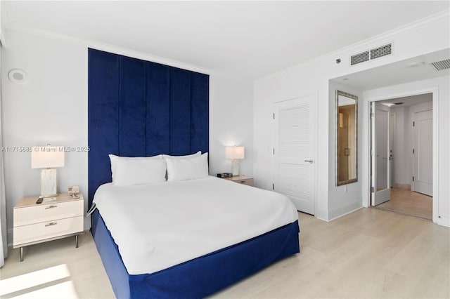 bedroom with a closet, light hardwood / wood-style floors, and ornamental molding