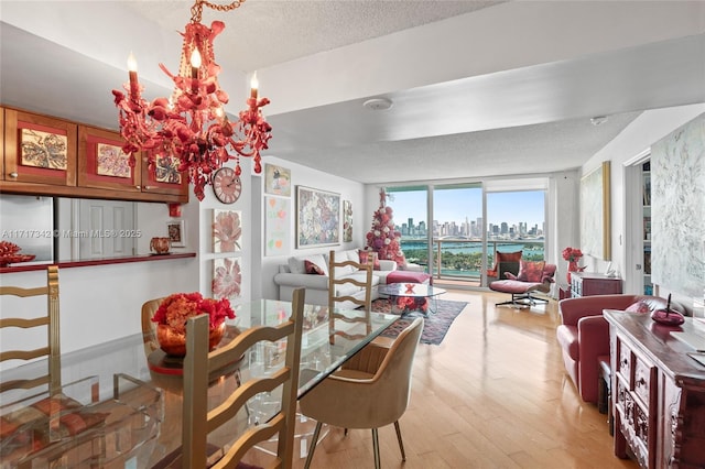 dining space featuring a notable chandelier, floor to ceiling windows, light hardwood / wood-style floors, and a textured ceiling