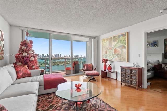 living room featuring a water view, hardwood / wood-style floors, expansive windows, and a textured ceiling