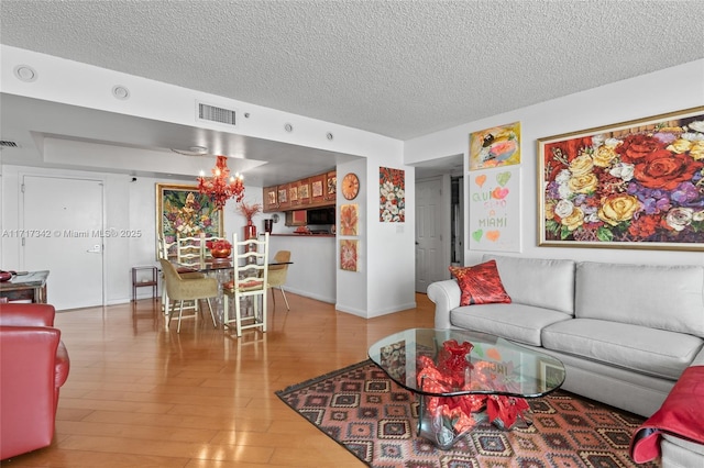 living room with hardwood / wood-style floors, a chandelier, and a textured ceiling