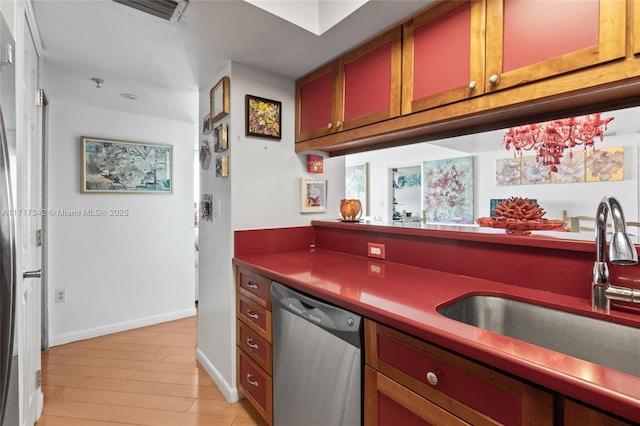 kitchen with stainless steel dishwasher, light wood-type flooring, sink, and an inviting chandelier