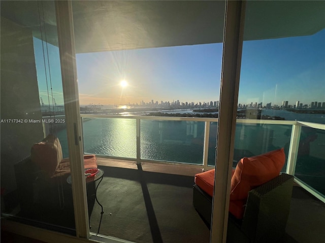 balcony at dusk featuring a water view