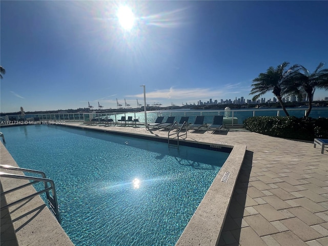 view of pool with a patio area and a water view