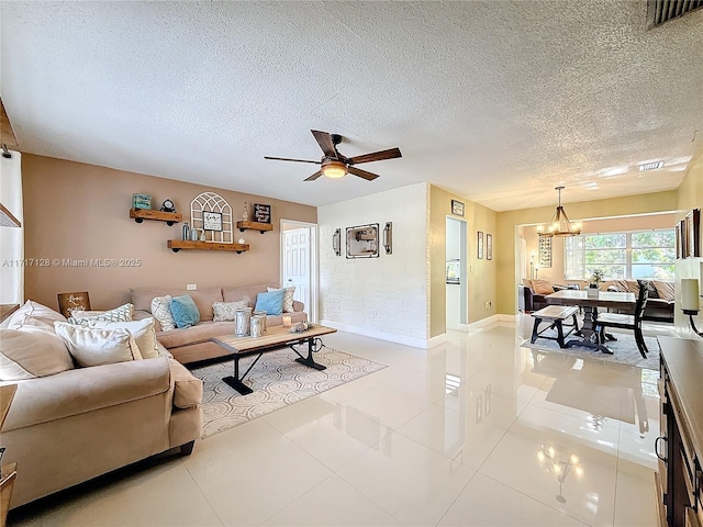 living room with light tile patterned floors, ceiling fan with notable chandelier, and a textured ceiling