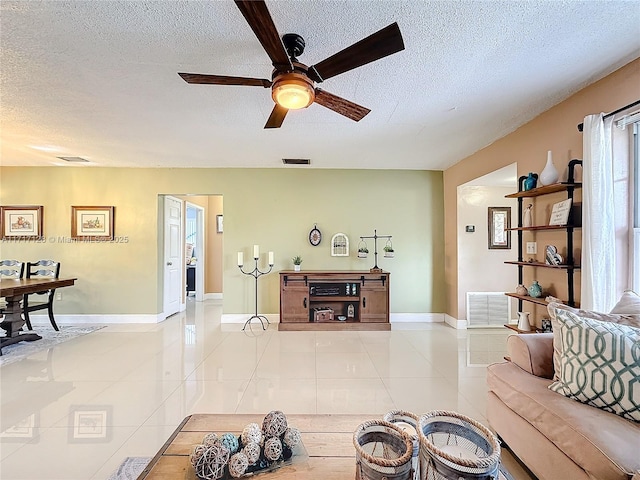 living room with a textured ceiling, ceiling fan, and light tile patterned flooring