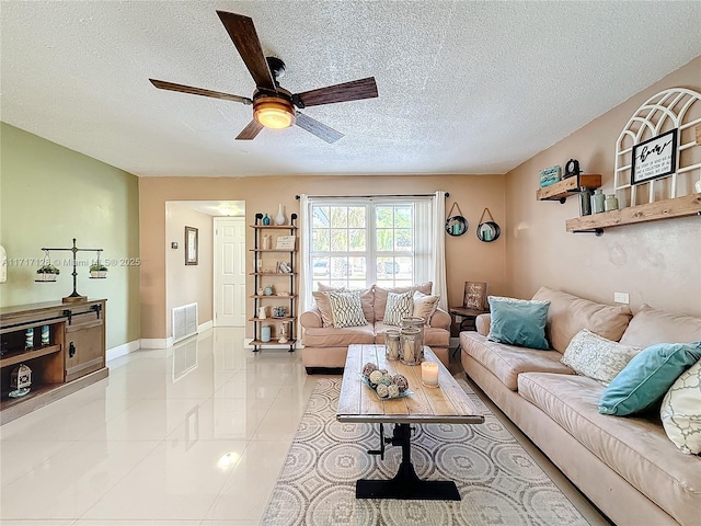 tiled living room with ceiling fan and a textured ceiling